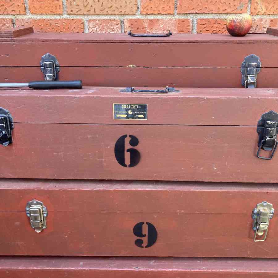 Cajas rojas de atrezo vintage usadas por equipos de iluminación de cine, colocadas en un backstage de rodaje