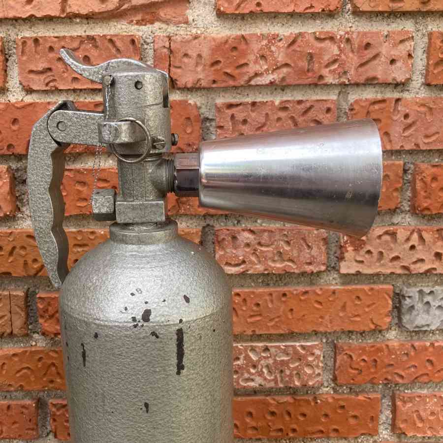 Extintor gris metálico vintage de época usado como atrezo en escenarios, pasillos o backstage.