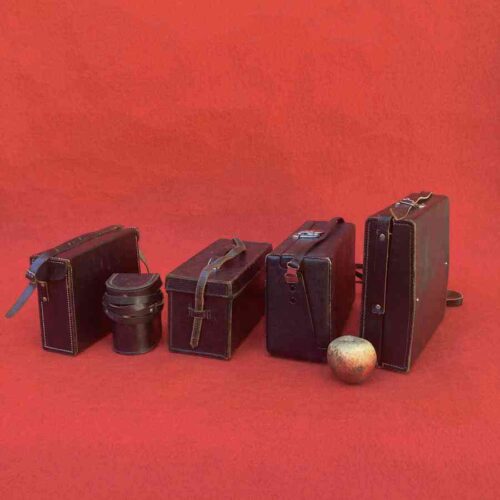 Maletines técnicos vintage de reportero gráfico en cuero oscuro, años 60-70, usados junto a cámaras fotográficas y de cine.