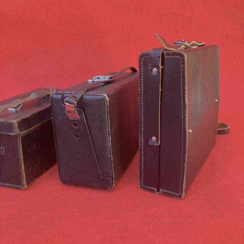 Maletines técnicos vintage de reportero gráfico en cuero oscuro, años 60-70, usados junto a cámaras fotográficas y de cine.